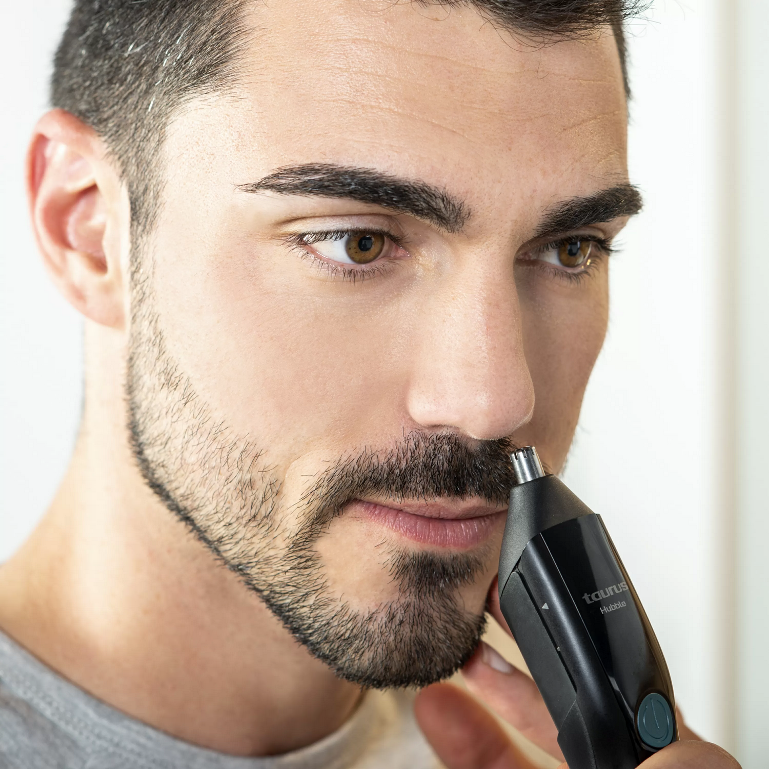 Hombre usando un recortador de vello nasal, primer plano.