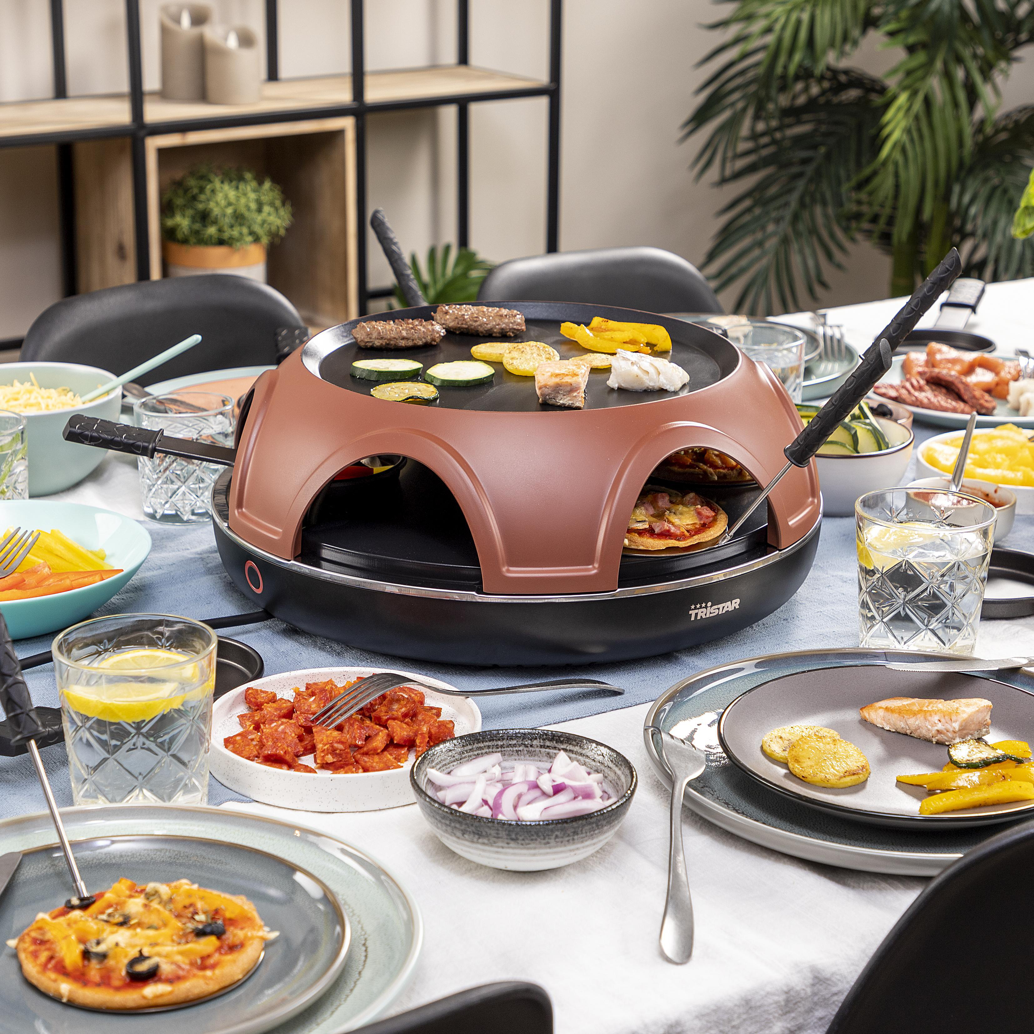 Raclette-Grill mit gekochtem Essen, plus Tellern mit Essen und Getränken auf einem Tisch.