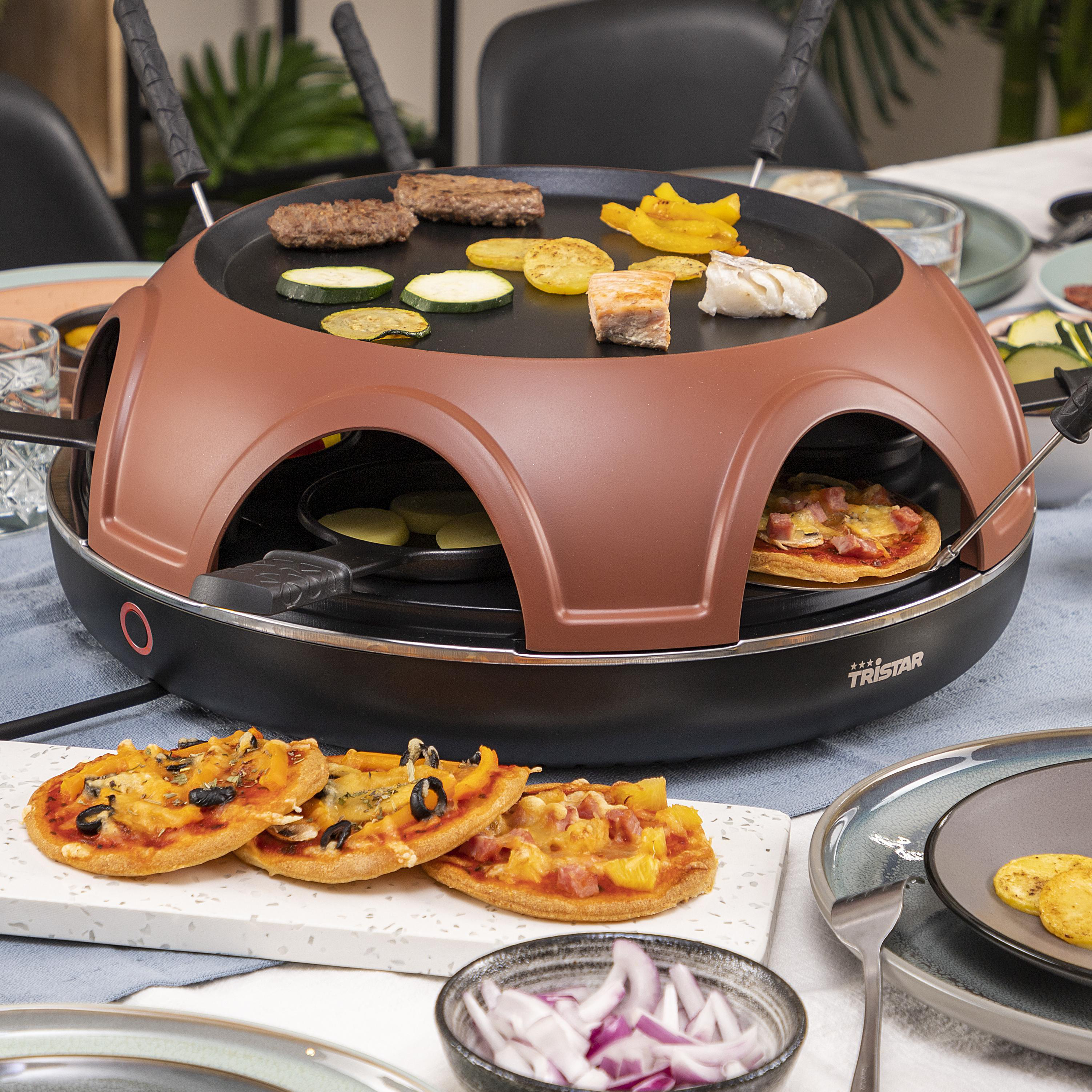 Raclette-Grill mit Essen, darunter Mini-Pizzas und gegrilltes Gemüse.