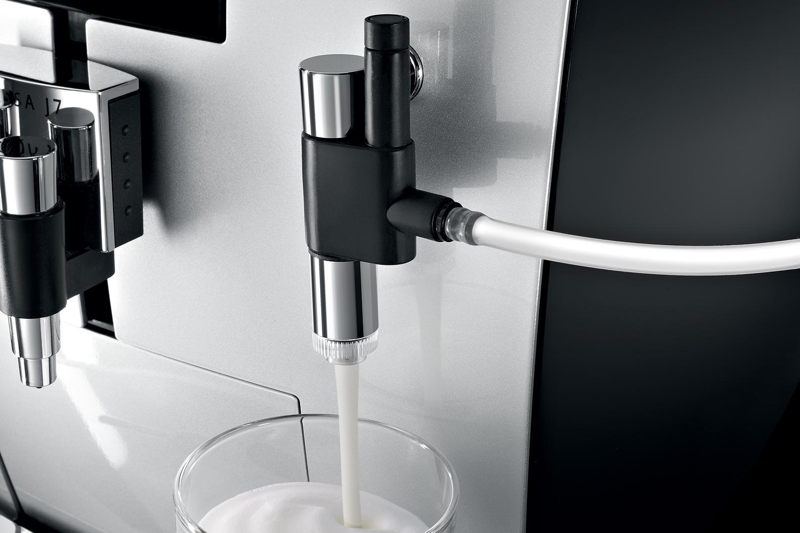 Eine Kaffeemaschine, die Milch in ein Glas abgibt.