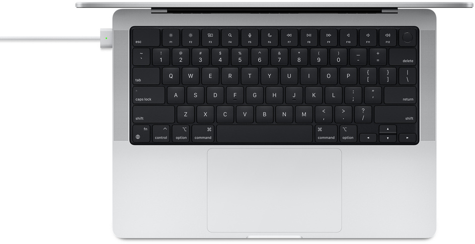 Vue de dessus d'un ordinateur portable argenté avec clavier noir et câble de charge blanc.