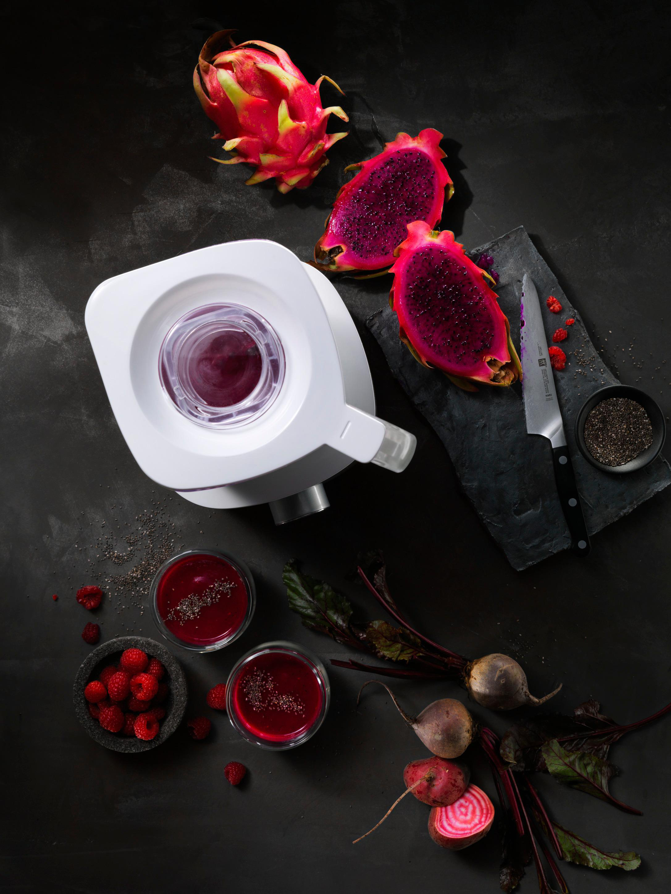 Draufsicht auf einen Mixer mit Drachenfrucht- und Rote-Bete-Saft, geschnittener Drachenfrucht und Chiasamen.