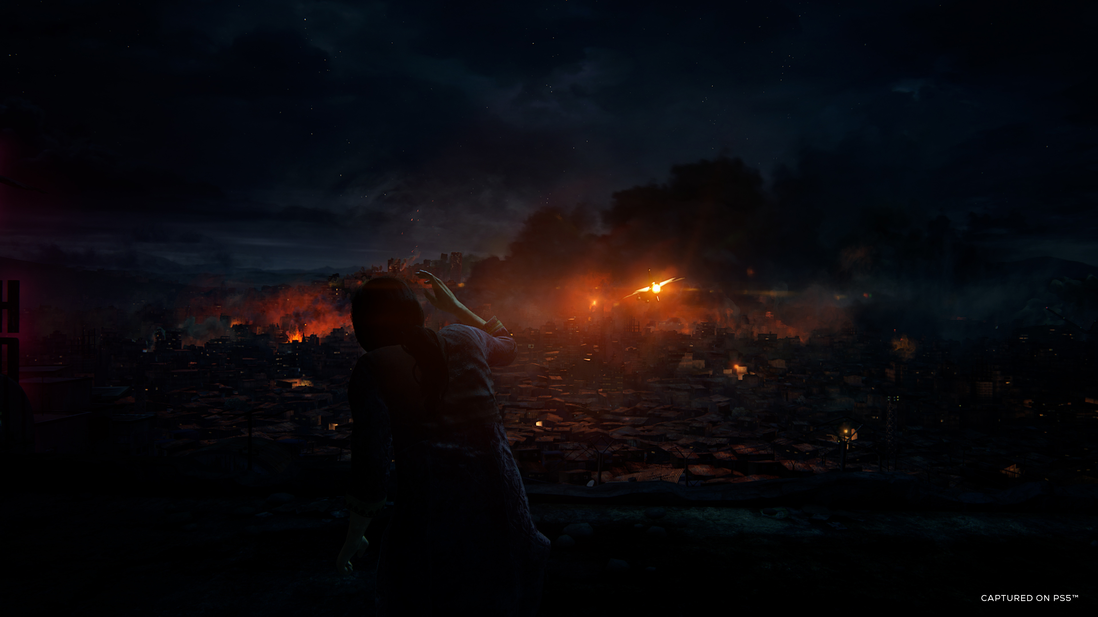 Person auf einem Dach mit Blick auf eine Stadt, die nachts von Feuer verschlungen wird, mit feurigem Himmel.