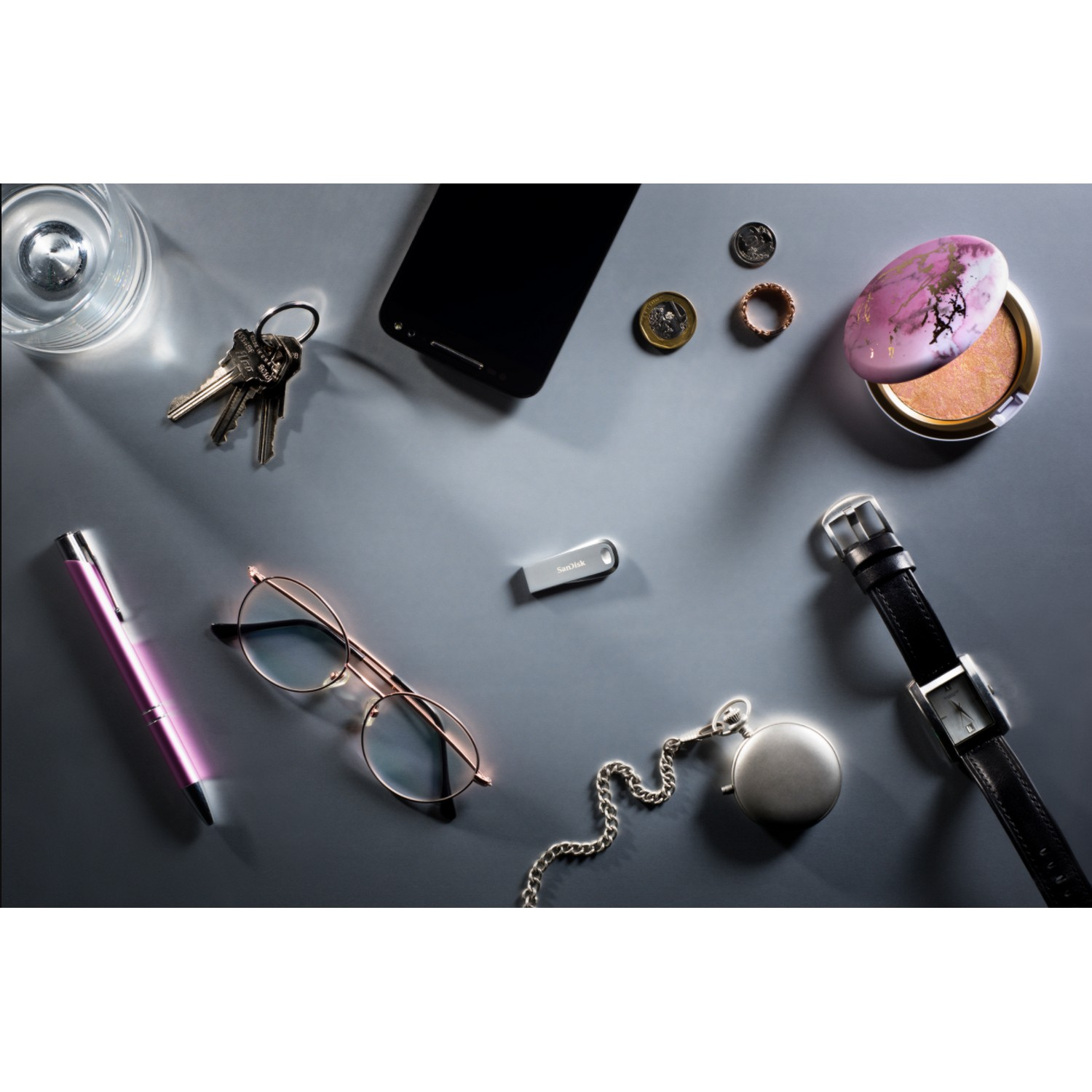 Varios objetos: llaves, gafas, bolígrafo, monedas, reloj, memoria USB y maquillaje.