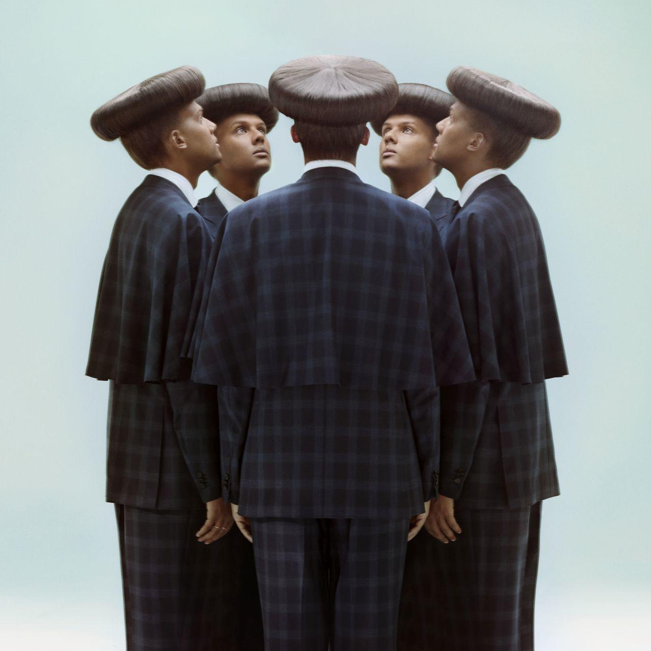 Six hommes en costume se font face en cercle. Ils portent les mêmes vêtements et chapeaux.