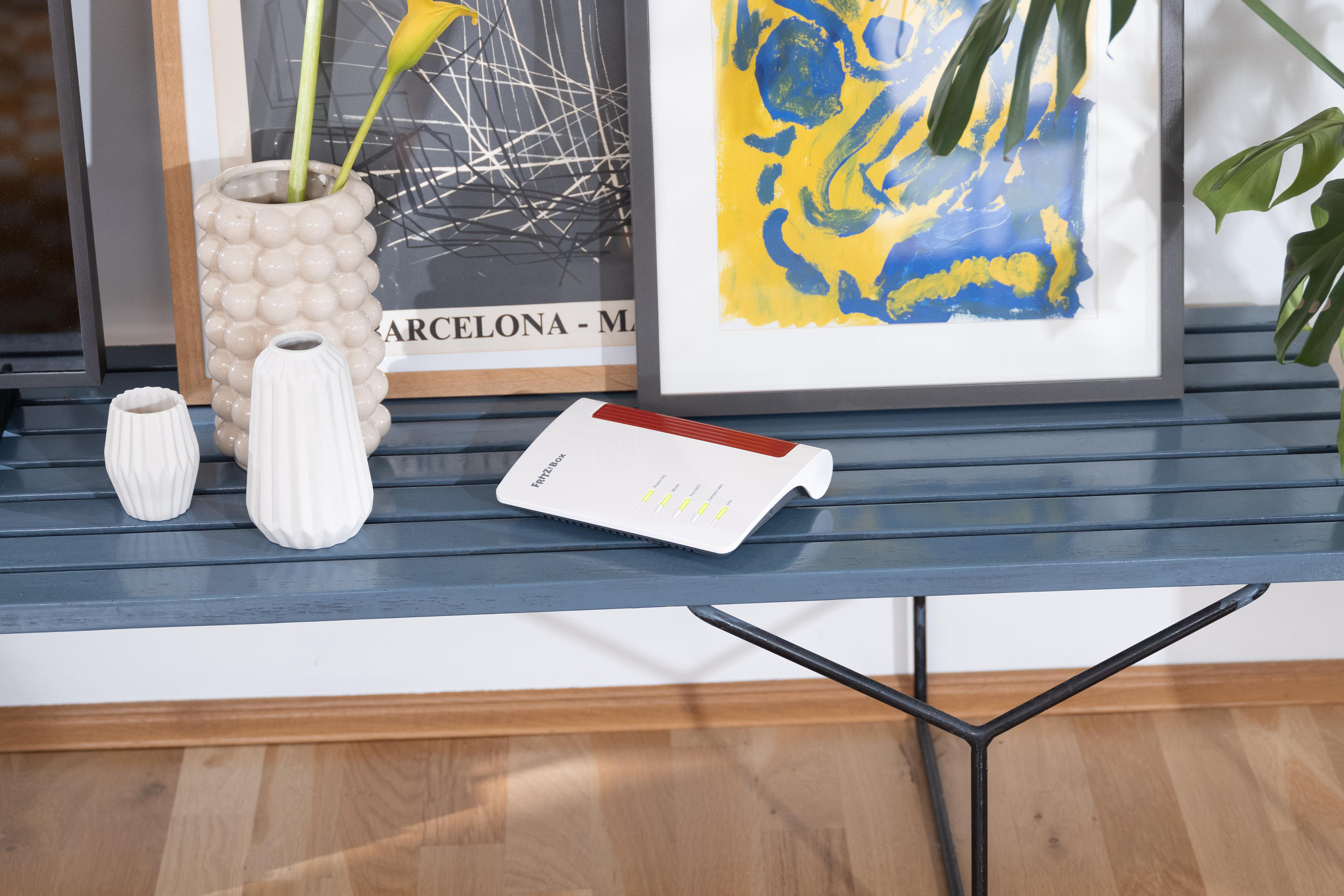 Weißer Router auf blauem Tisch mit Kunst und Vasen.