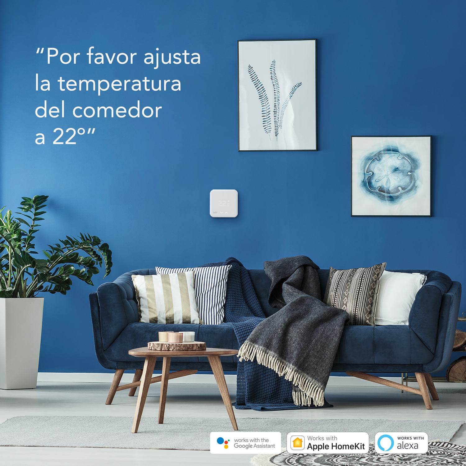 Una pared azul con un dispositivo de hogar inteligente, sofá e impresiones artísticas. Texto: "Por favor, ajusta..."