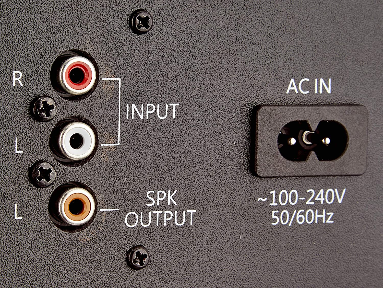 Közeli kép az audioeszköz be- és kimeneteiről. RCA bemeneteket, hangszóró kimeneteket és egy AC bemenetet tartalmaz. Szöveges címkék is láthatók.