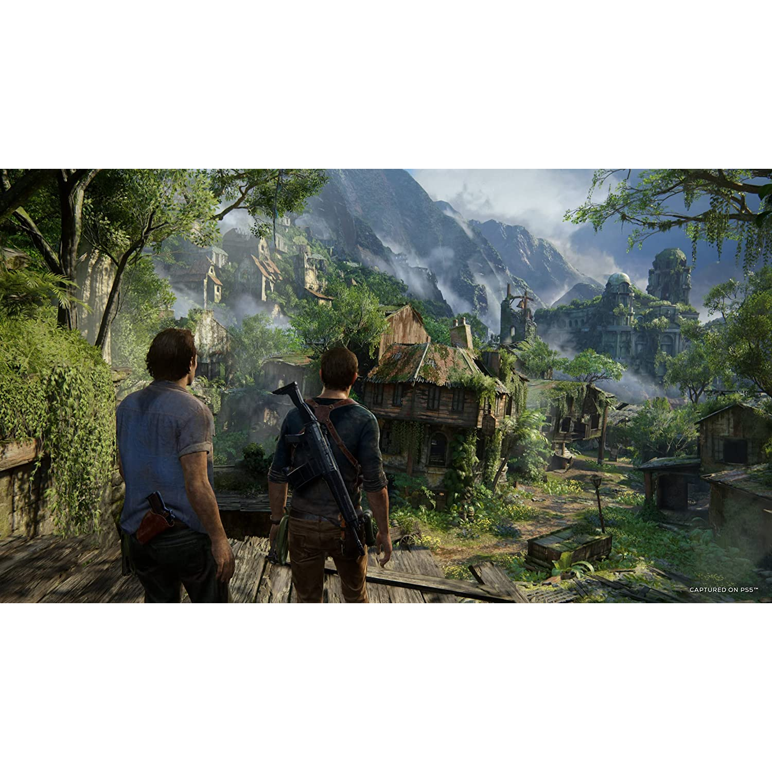 Dos hombres mirando un pueblo en la jungla, montañas al fondo.