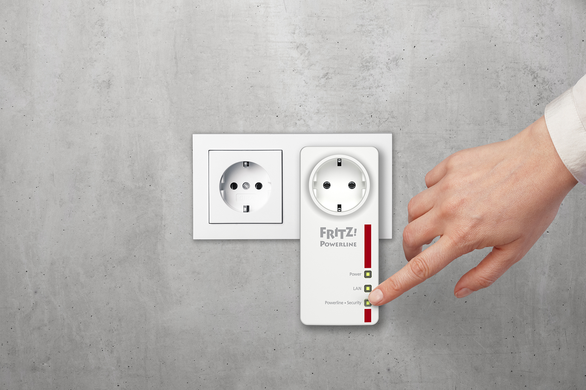 Hand touching a Frit! Powerline adapter plugged into wall outlet. Two lights on.