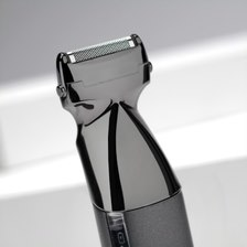 Gros plan d'une tête de rasoir électrique gris foncé. La lame est visible, inclinée vers le spectateur.