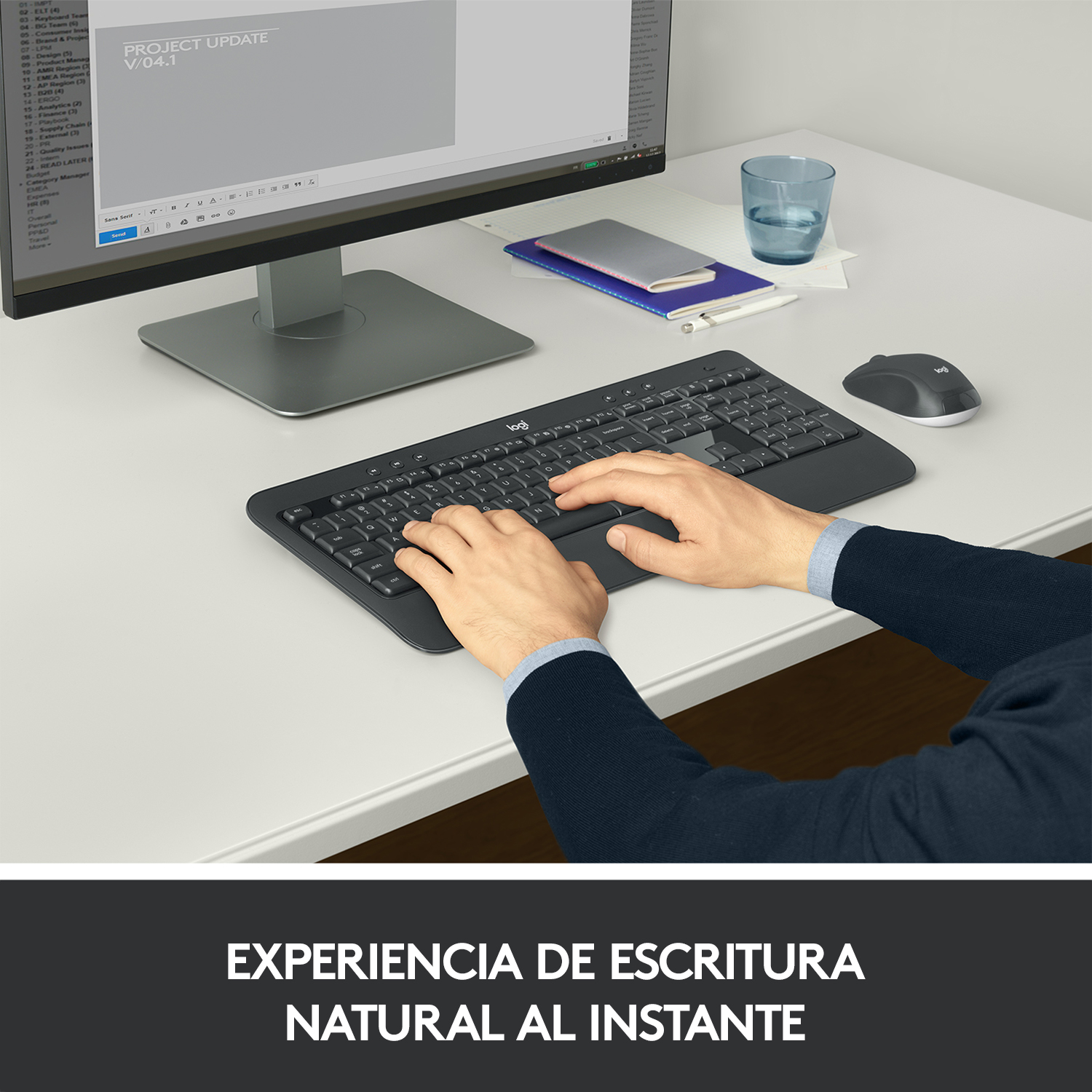 Manos de una persona tecleando en un teclado negro, con monitor y ratón sobre un escritorio blanco.