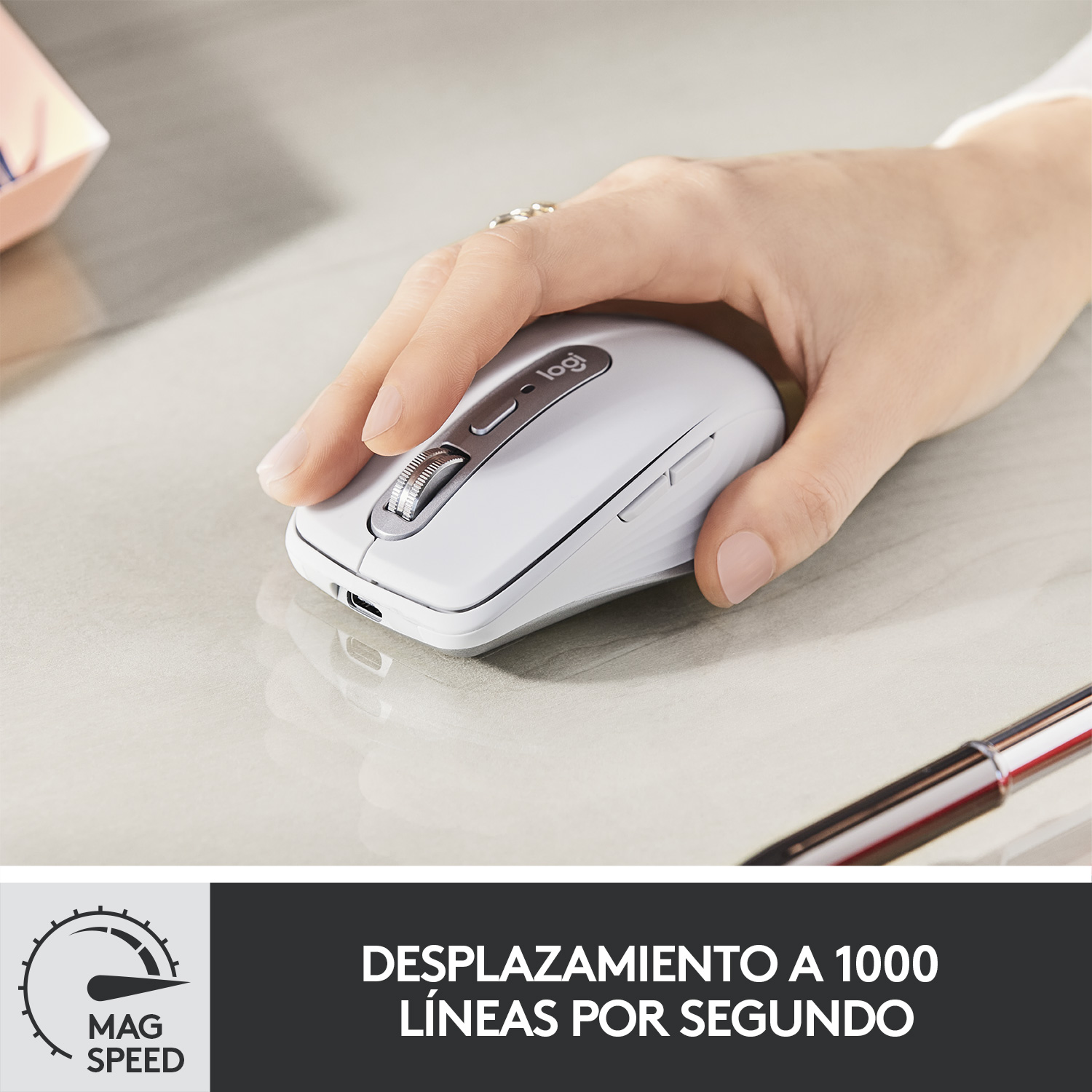 Una mano utiliza un ratón blanco en un escritorio. El ratón tiene una rueda de desplazamiento y un logotipo.