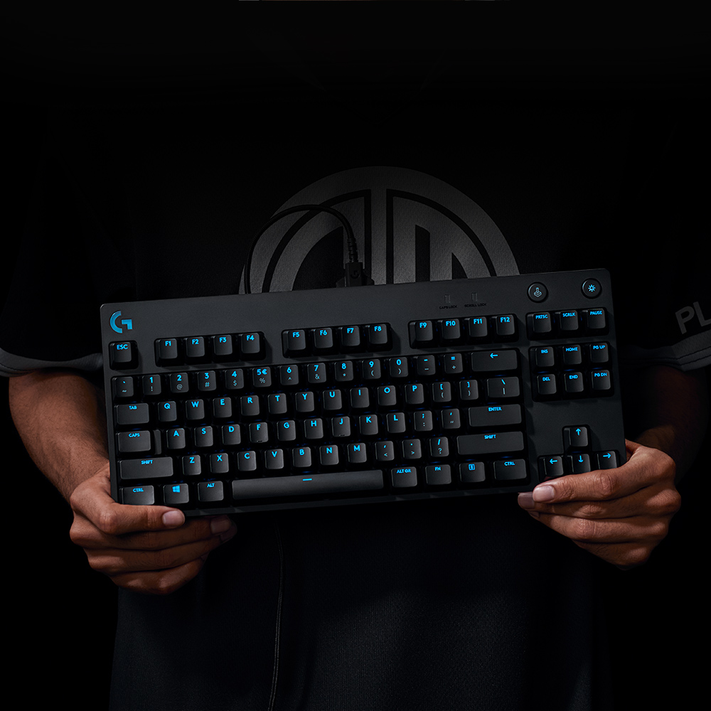 Black keyboard held by hands. Blue backlit keys, black keys, and the Logitech logo.