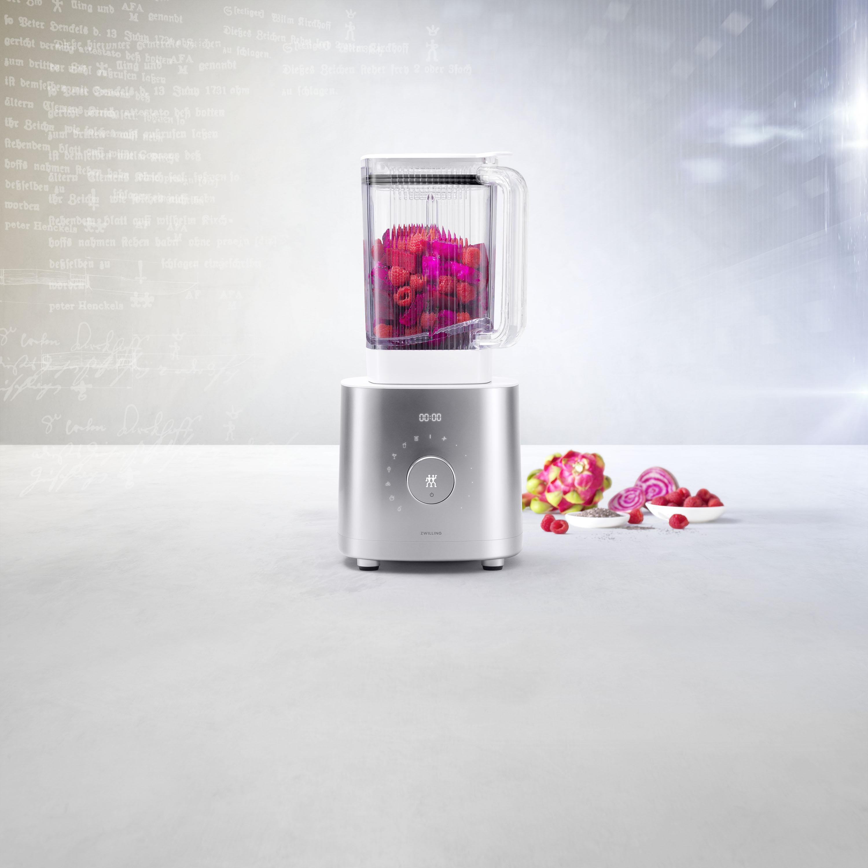 Ein Mixer mit einem transparenten Behälter, gefüllt mit roten Früchten. Darunter eine silberne Basis mit Digitalanzeige.