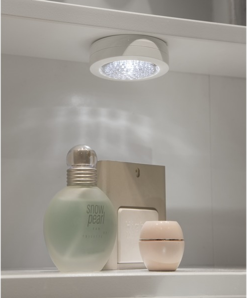 Lumière de plafond allumée au-dessus d'une étagère avec parfum et crèmes.