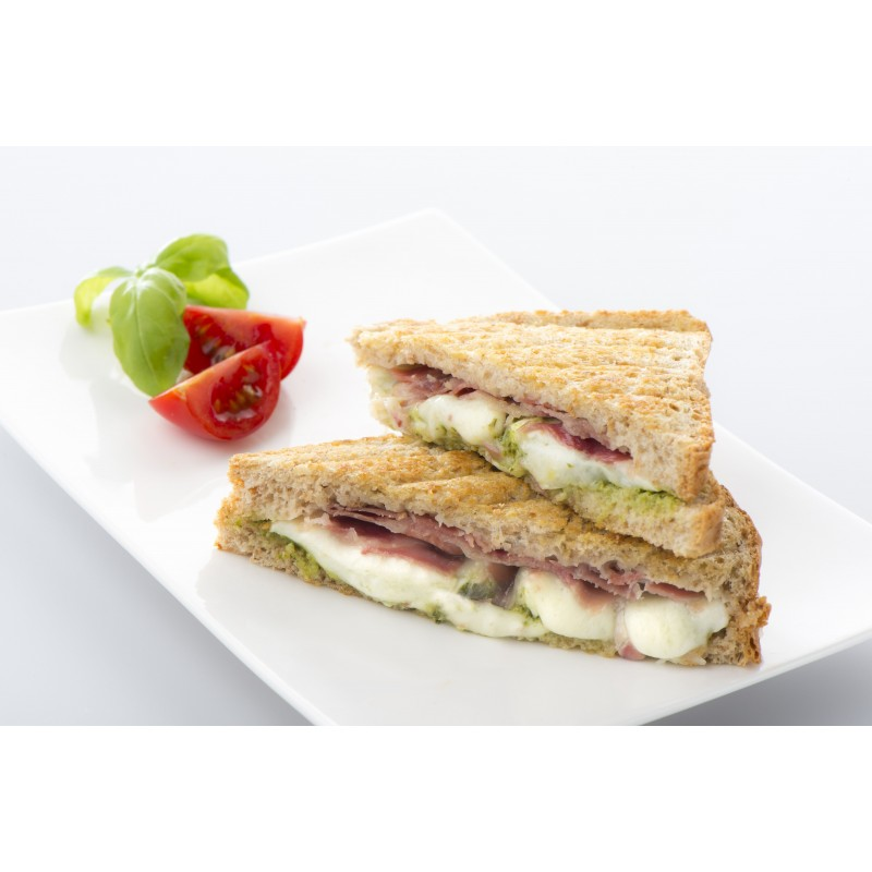 Two sandwiches with pesto, ham, and mozzarella on a white plate.