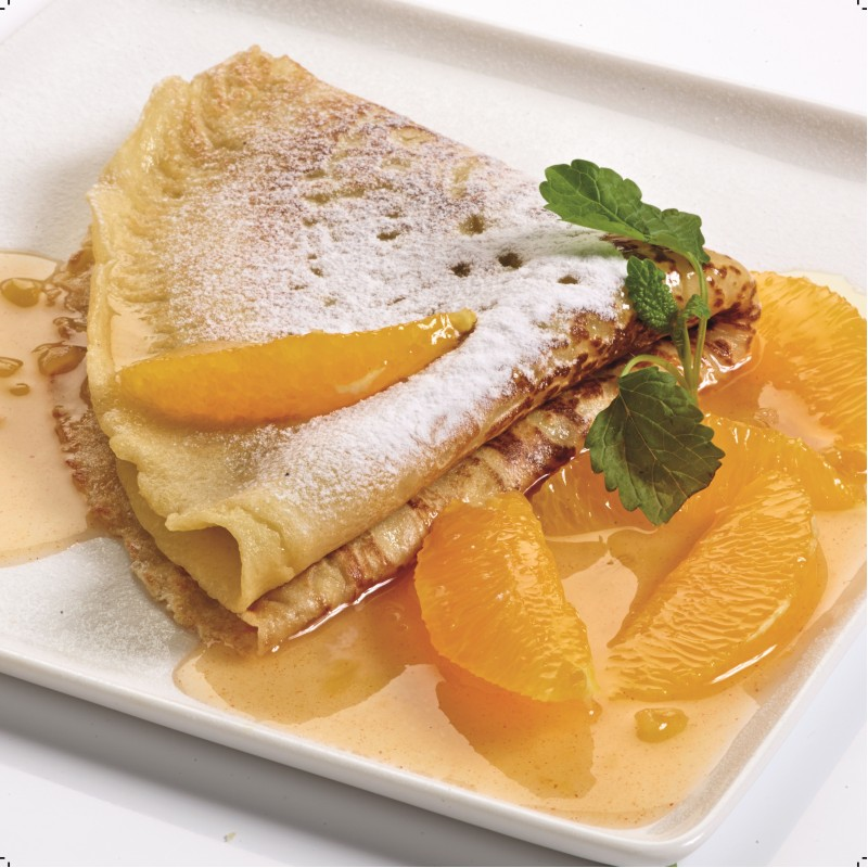 A plate with pancakes, orange slices, and syrup. Powdered sugar is sprinkled on the pancakes.