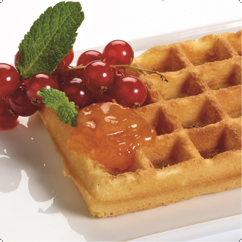 A waffle with red currants, mint, and orange jam on a white plate.