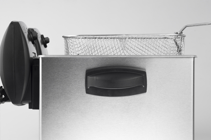 A deep fryer detail, stainless steel body, basket inside, black handle and control panel on the left.