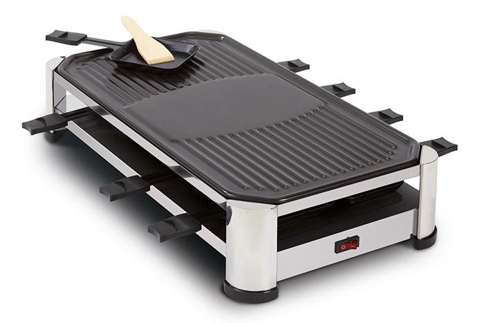 A raclette grill with a black cooking surface and a wooden spatula. The grill is silver and has a red power switch.