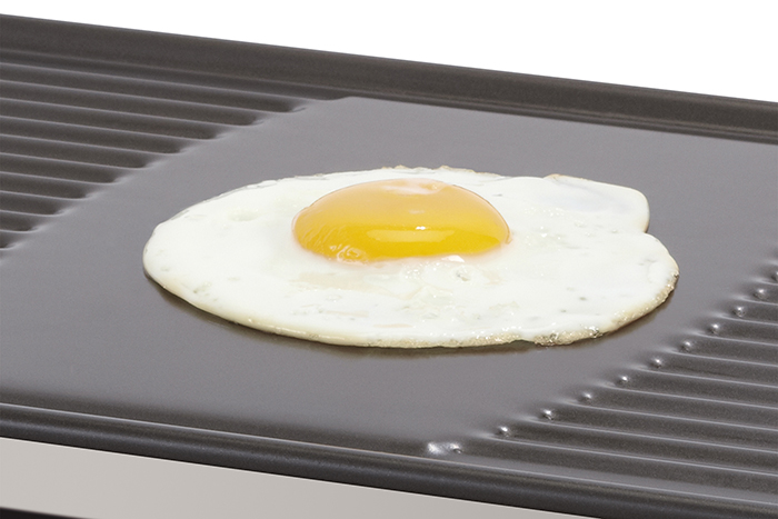 A fried egg on a black griddle with ridges. The yolk is yellow.