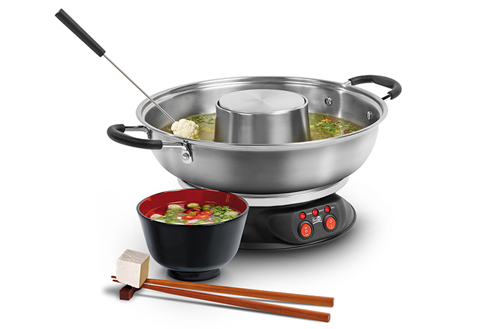 Een roestvrijstalen fondueset met een zwarte kom, eetstokjes en een dienblad met tofu.