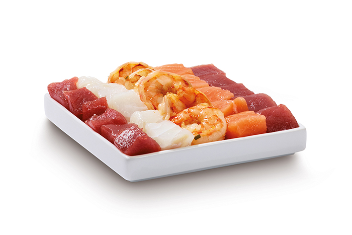 A white rectangular dish with seafood: shrimp, salmon, tuna, and white fish on a white background.