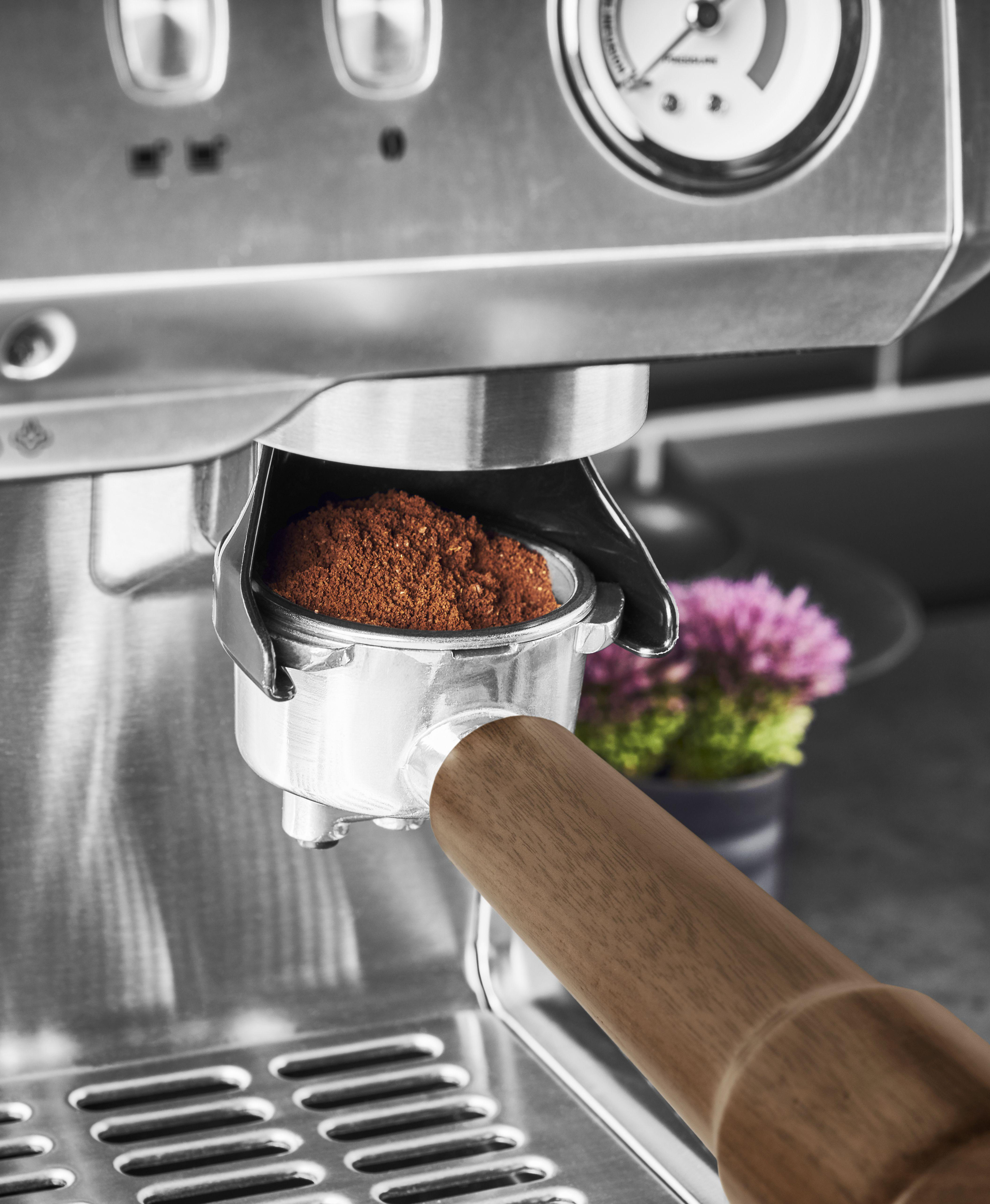 Kaffeemaschine mit Kaffeesatz im Siebträger, Holzgriff.