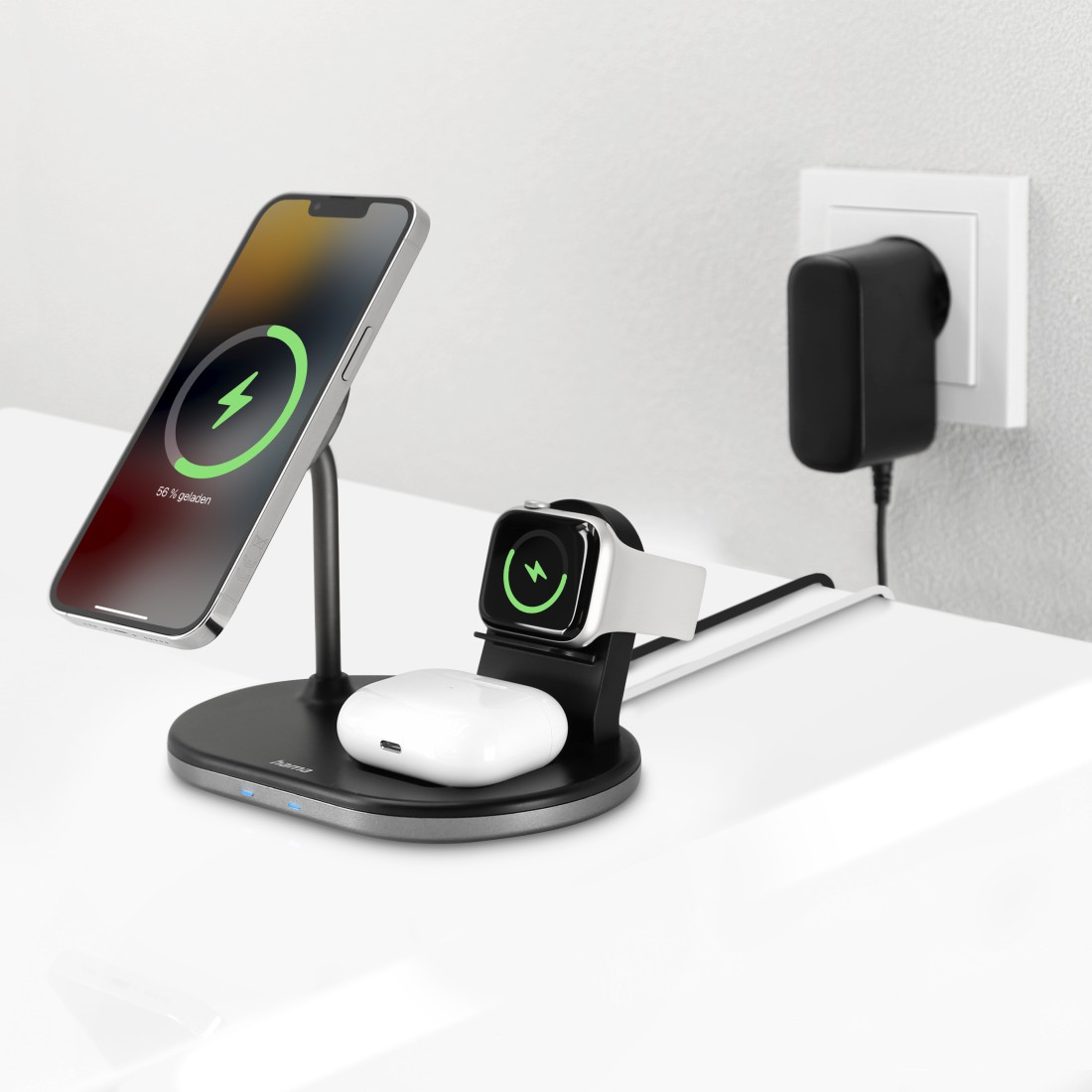 Kabellose Ladestation mit Handy, Uhr und Ohrhörern auf weißem Tisch.
