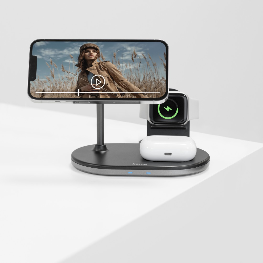 Eine Ladestation mit Telefon, Uhr und Ohrhörern auf einer weißen Oberfläche.