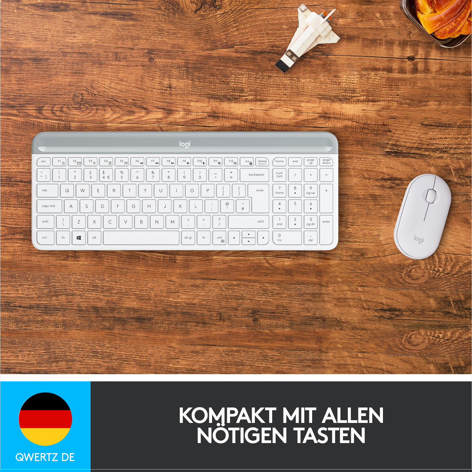 Eine weiße Tastatur und eine weiße Maus liegen auf einem Holzschreibtisch neben einem blau-gelben Logo.