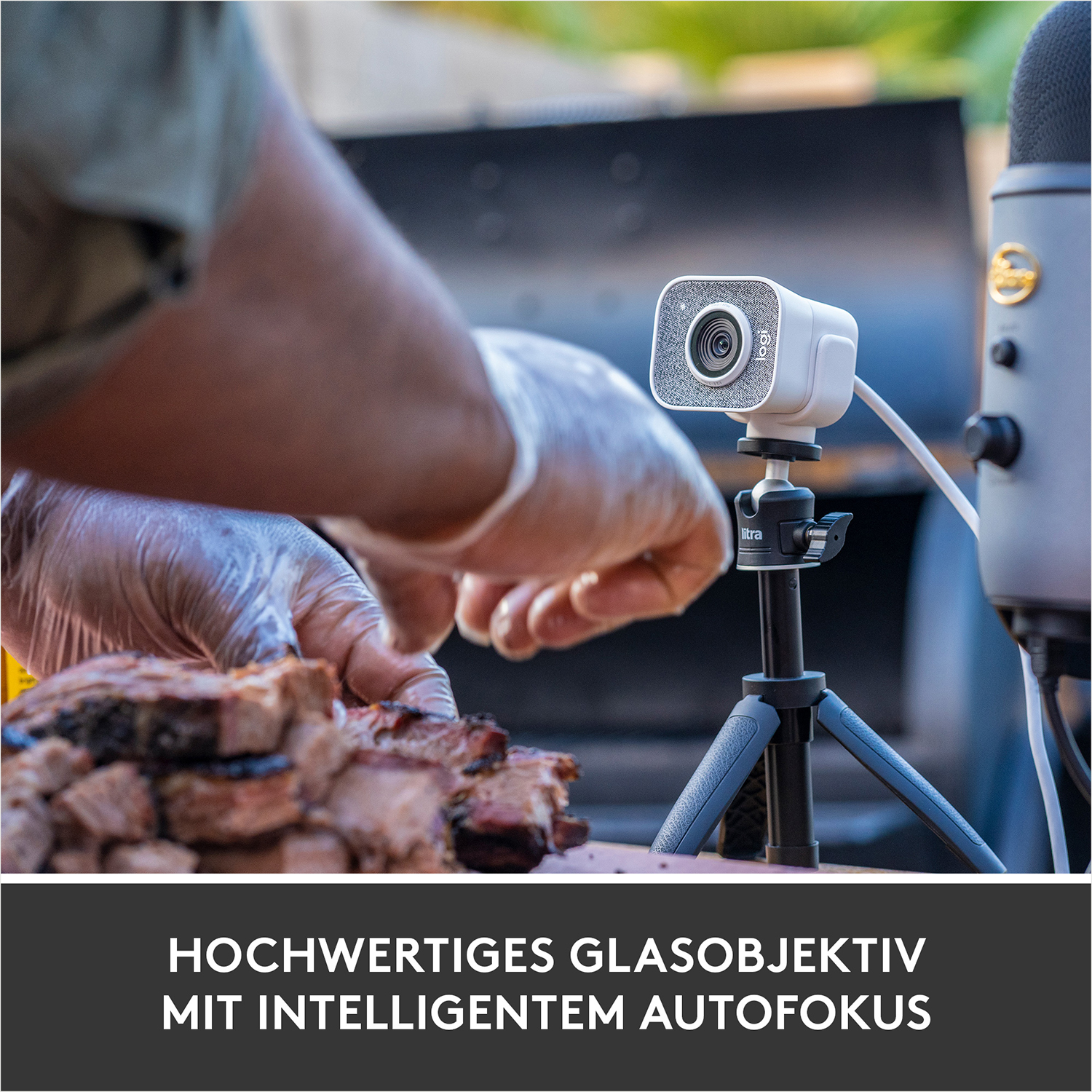 Eine Person legt das Essen vor die Kamera, mit einer weißen Webcam und einem Mikrofon.