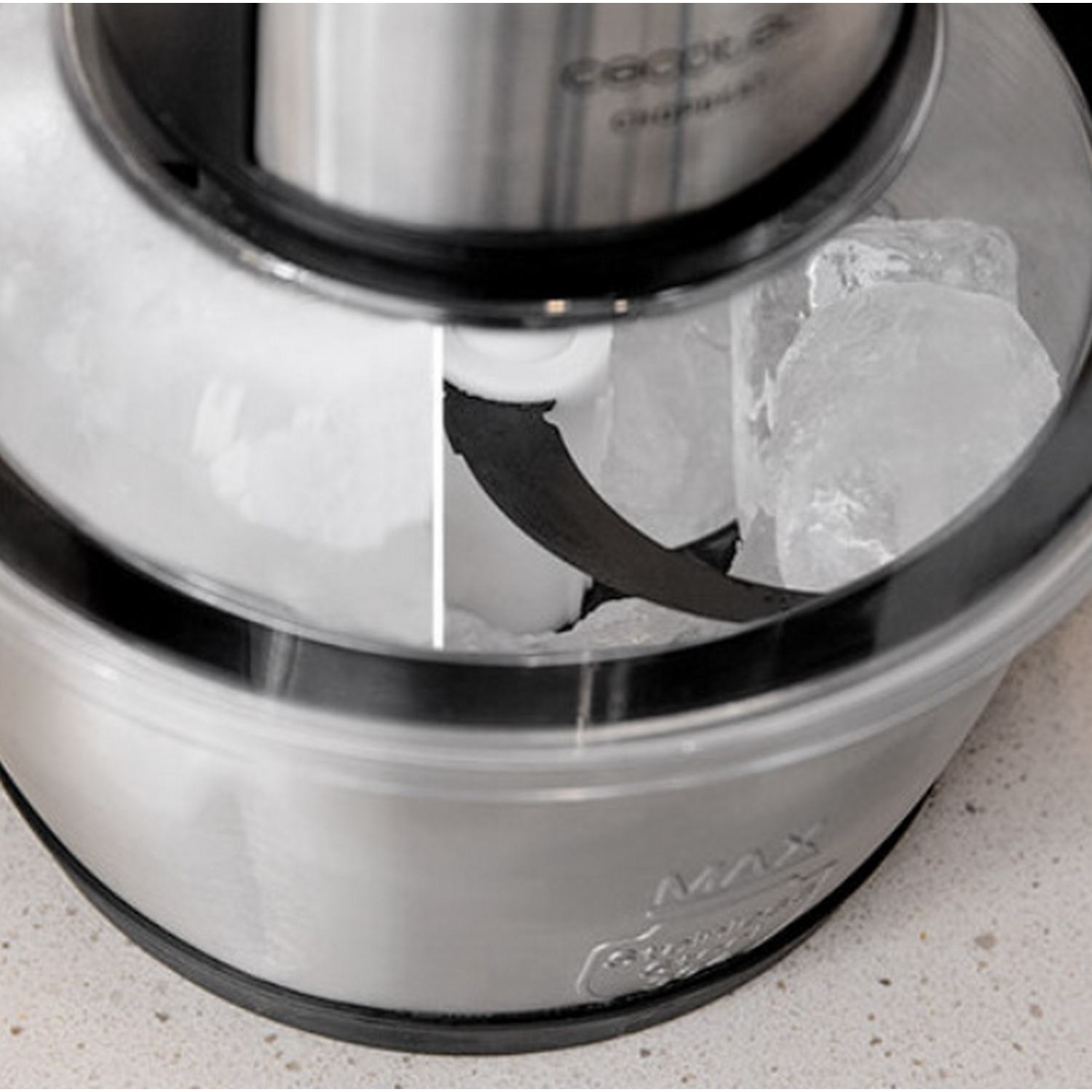 Máquina para hacer helados con hielo y una cuchilla dentro de un recipiente transparente.