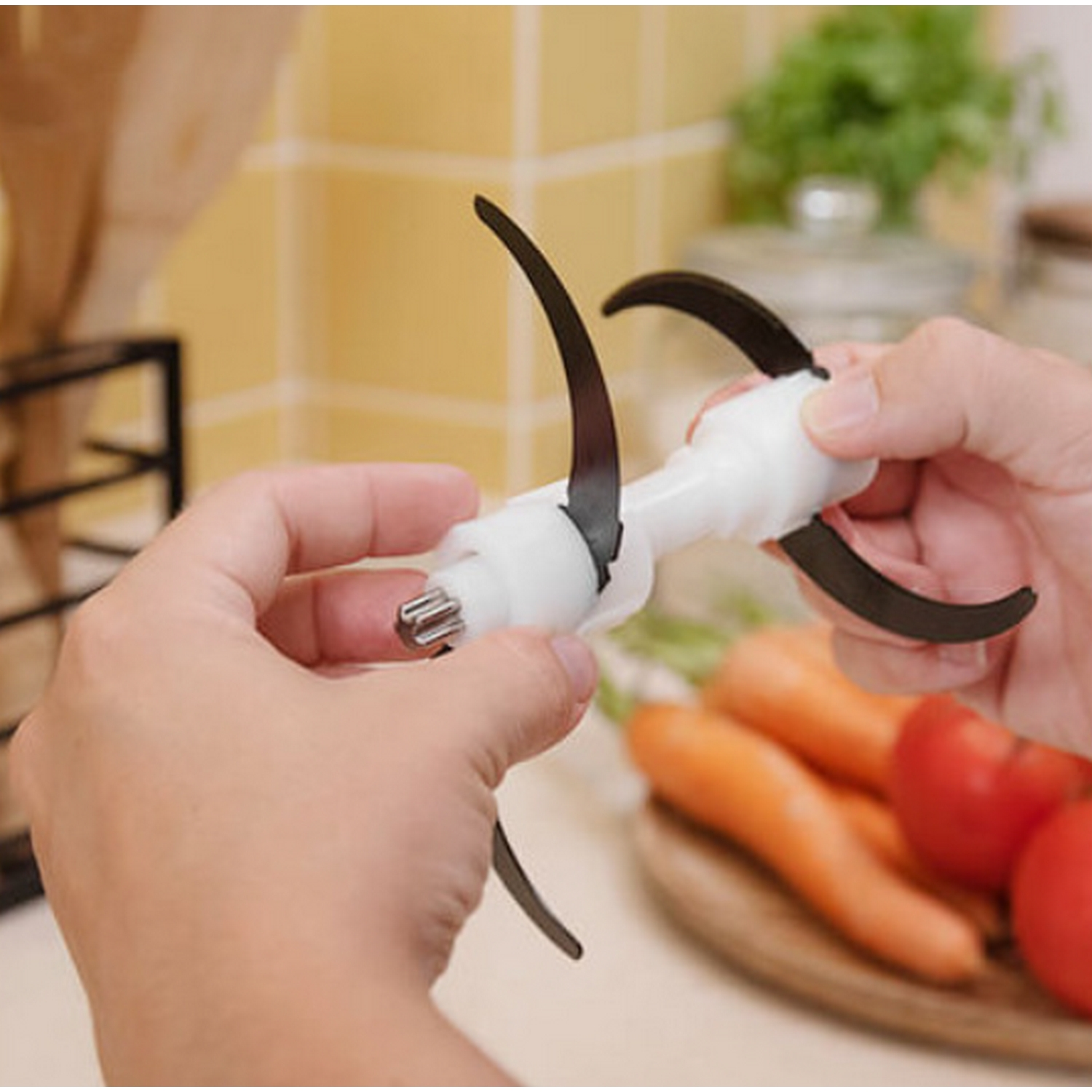 Manos sosteniendo una cuchilla de procesador de alimentos blanca con zanahoria y tomate.
