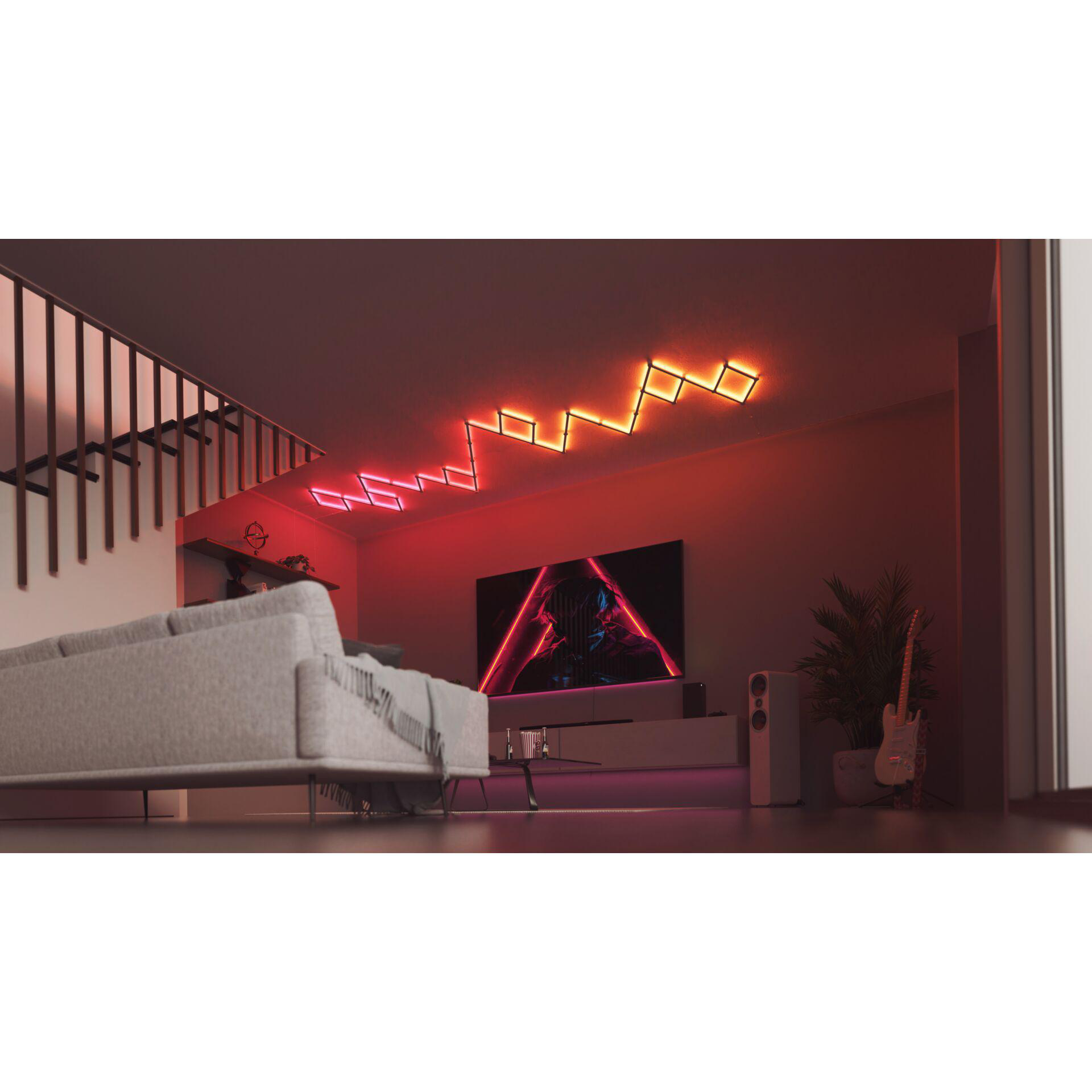 Wohnzimmer mit grauem Sofa, bunten Neonlichtern an der Decke und einer Gitarre.