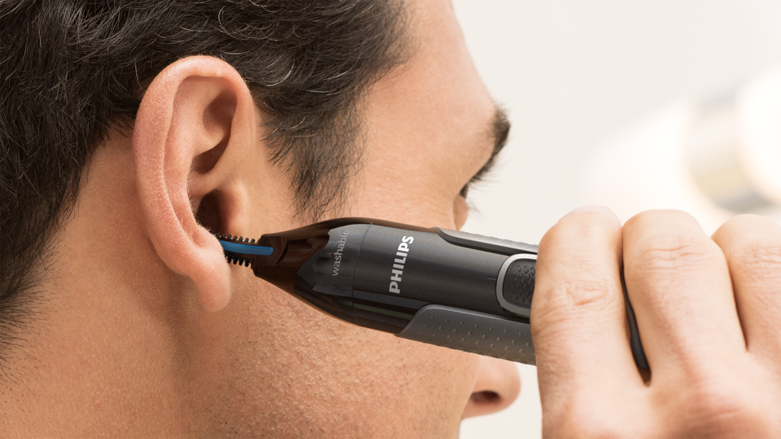 A man using a nose hair trimmer, close up on his face.