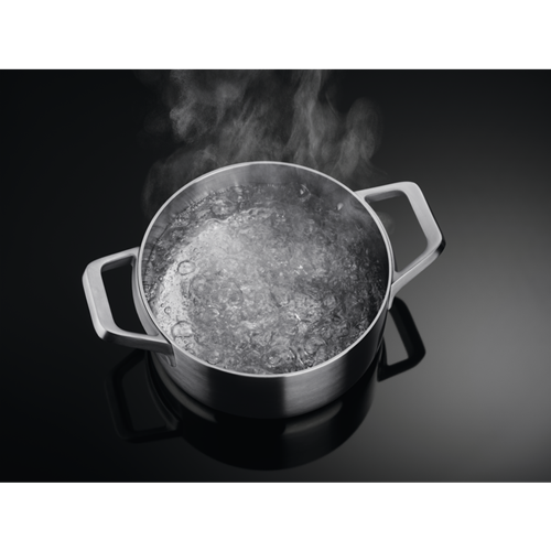 Kokend water in een roestvrijstalen pan met twee handvatten. Stoom komt omhoog.