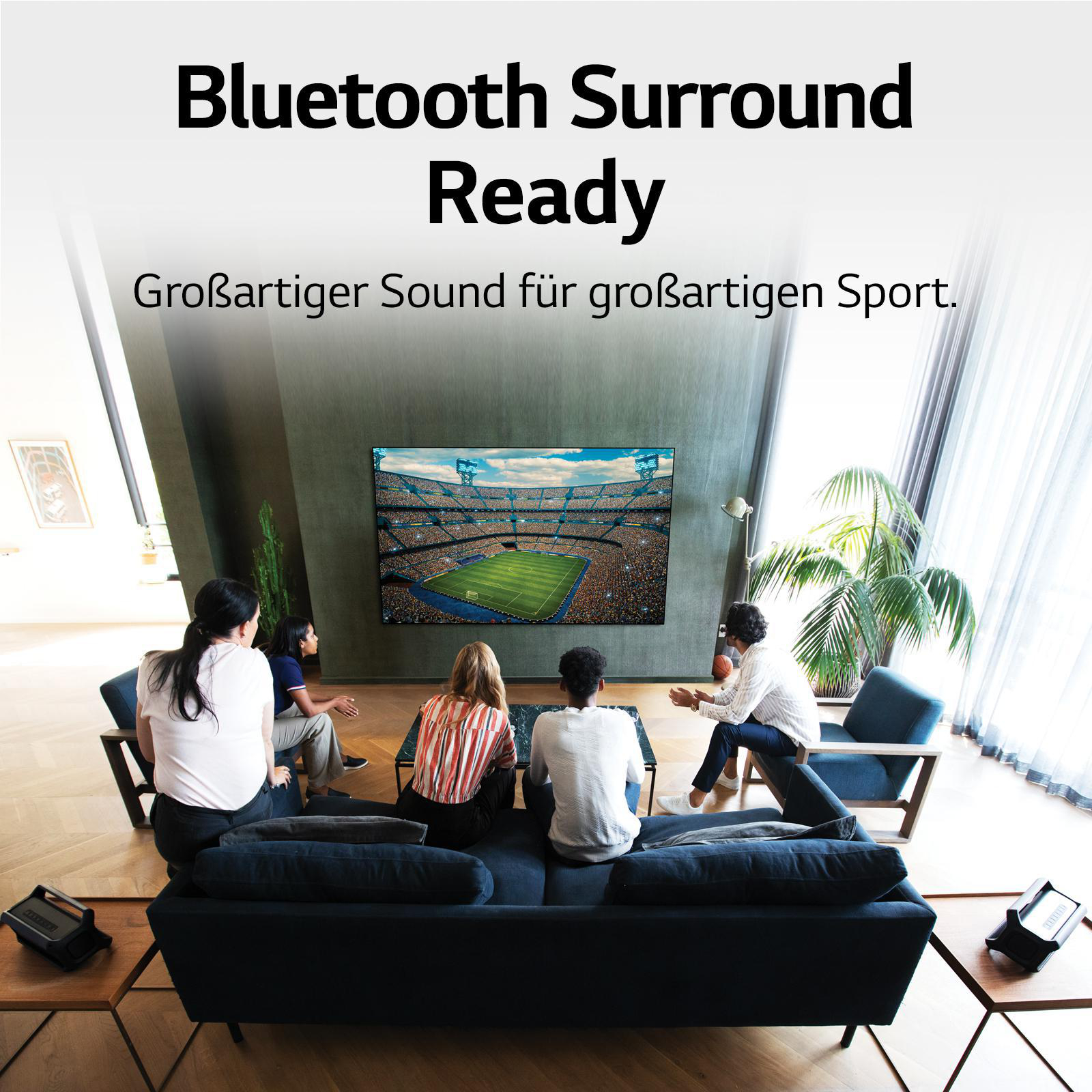 Menschen schauen ein Fußballspiel auf einem großen Fernseher. Text: Bluetooth Surround Ready.