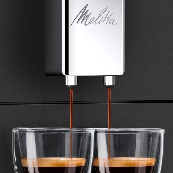 Espressomachine die koffie in twee glazen giet, op een donker oppervlak.