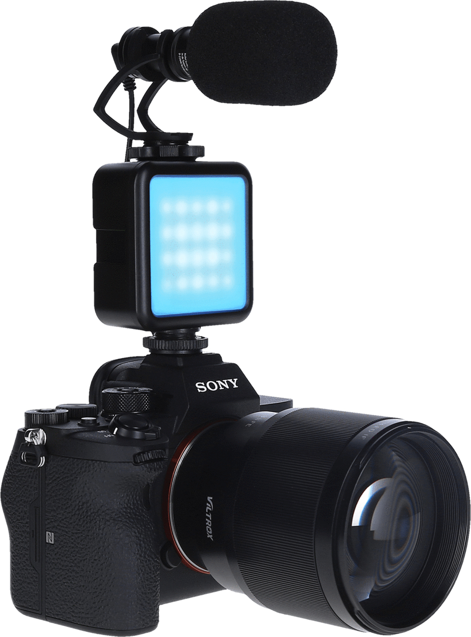 Un appareil photo Sony noir avec un objectif, une lumière et un microphone. La lumière est bleue, et le micro a une bonnette noire.