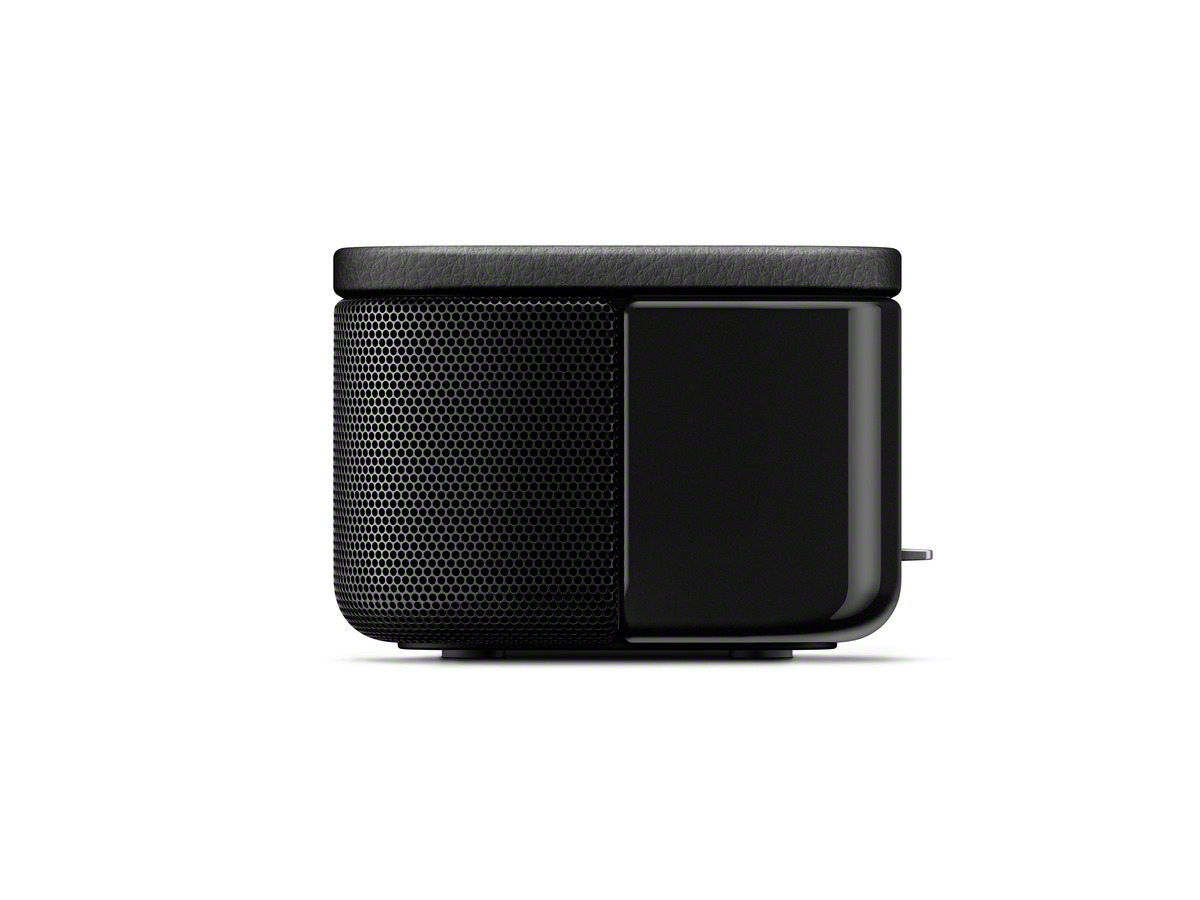 Altavoz negro con frontal de malla y parte superior de cuero. Está sobre una superficie blanca.