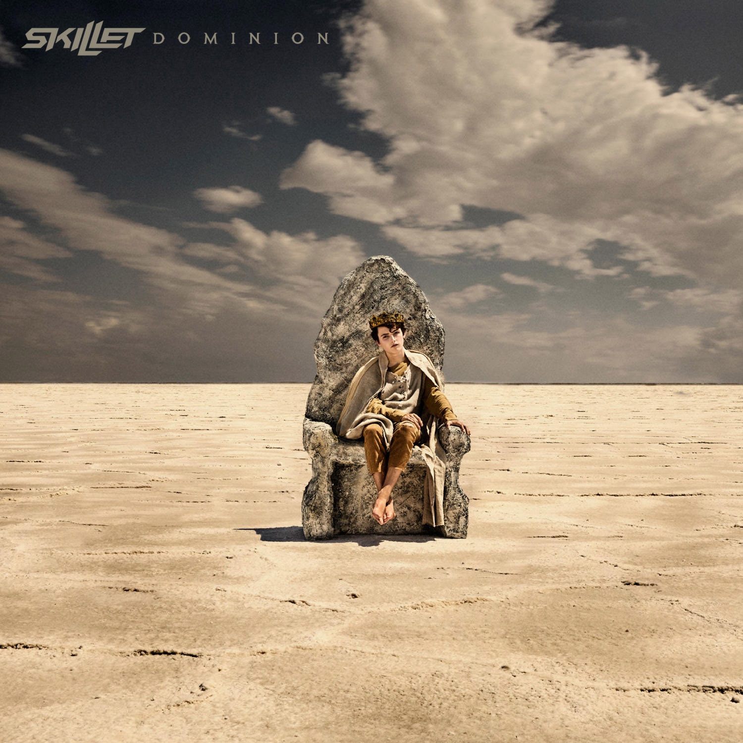 Albumcover: Ein Mann sitzt auf einem steinernen Thron in einer Wüstenlandschaft, Skillet - Dominion.