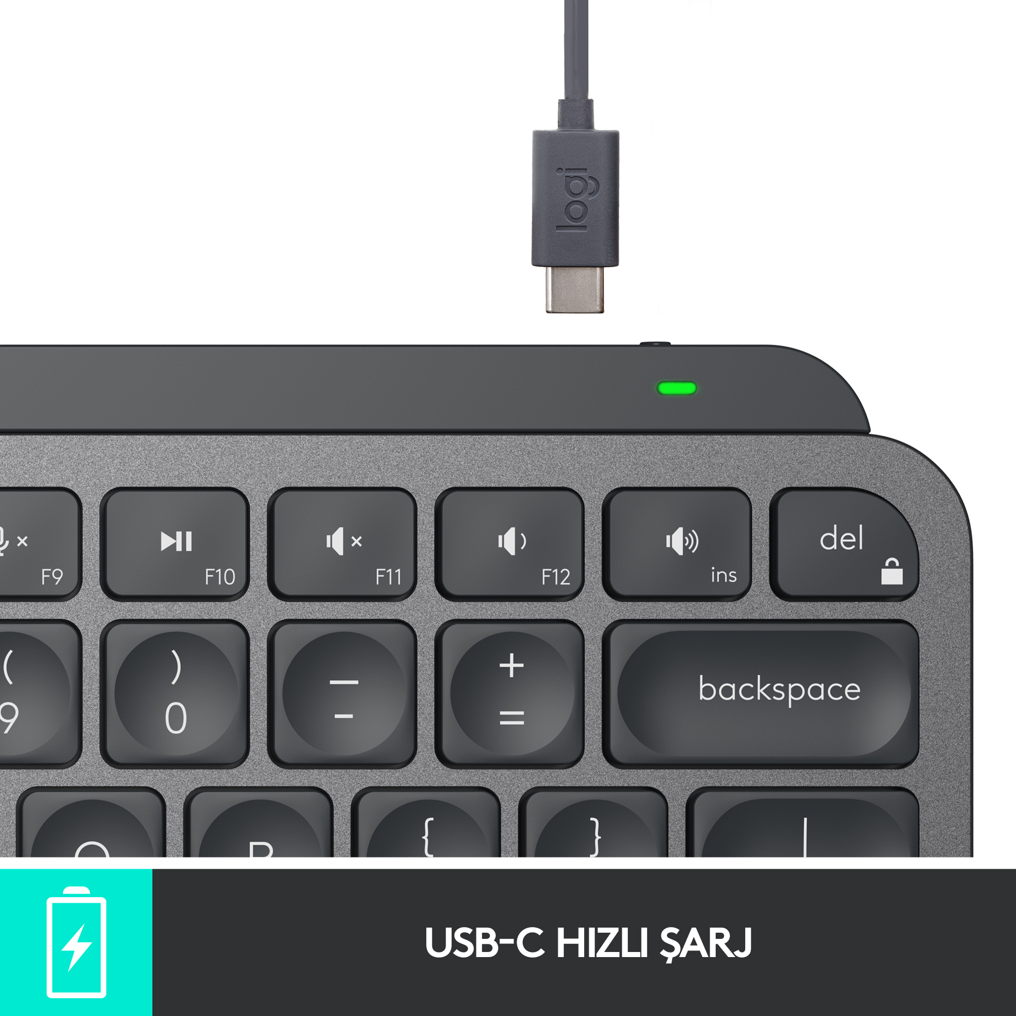 USB-C kablosu takılı koyu gri bir klavyenin yakın çekimi. Klavyede işlev tuşları ve geri tuşu bulunur.