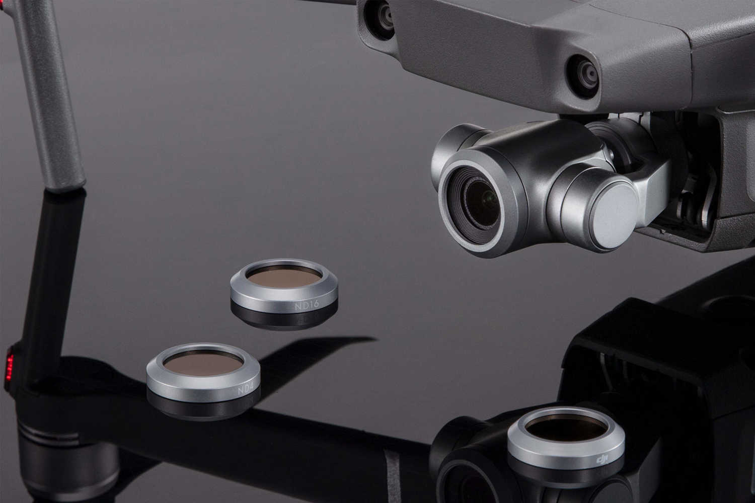 A drone with attached camera and three circular filters lying below. Filters are silver and brown in color.