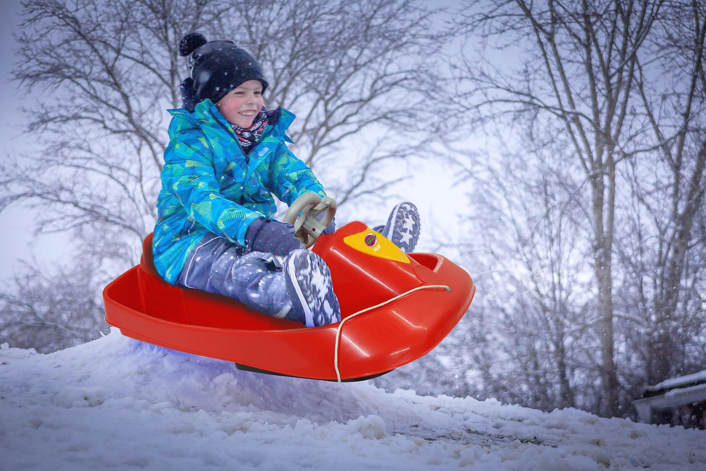 Junge rodelnd einen schneebedeckten Hügel hinunter auf einem roten Schlitten.