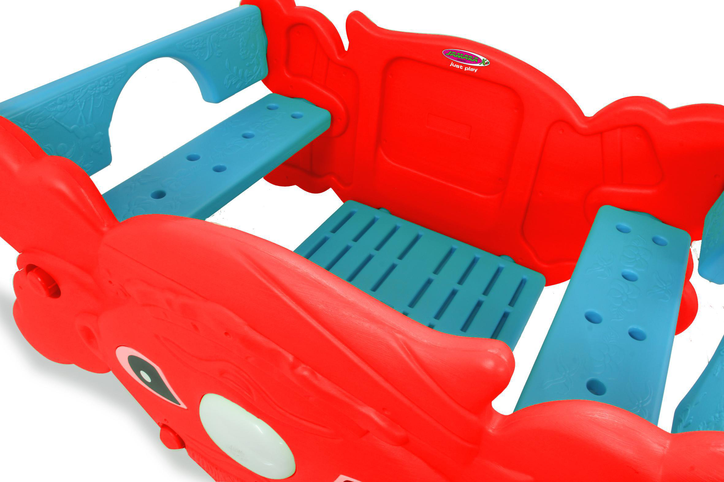 Rote und blaue Kunststoff-Spielstruktur. Mit Sitzgelegenheiten und einem kleinen blauen Boden, Schrägansicht.