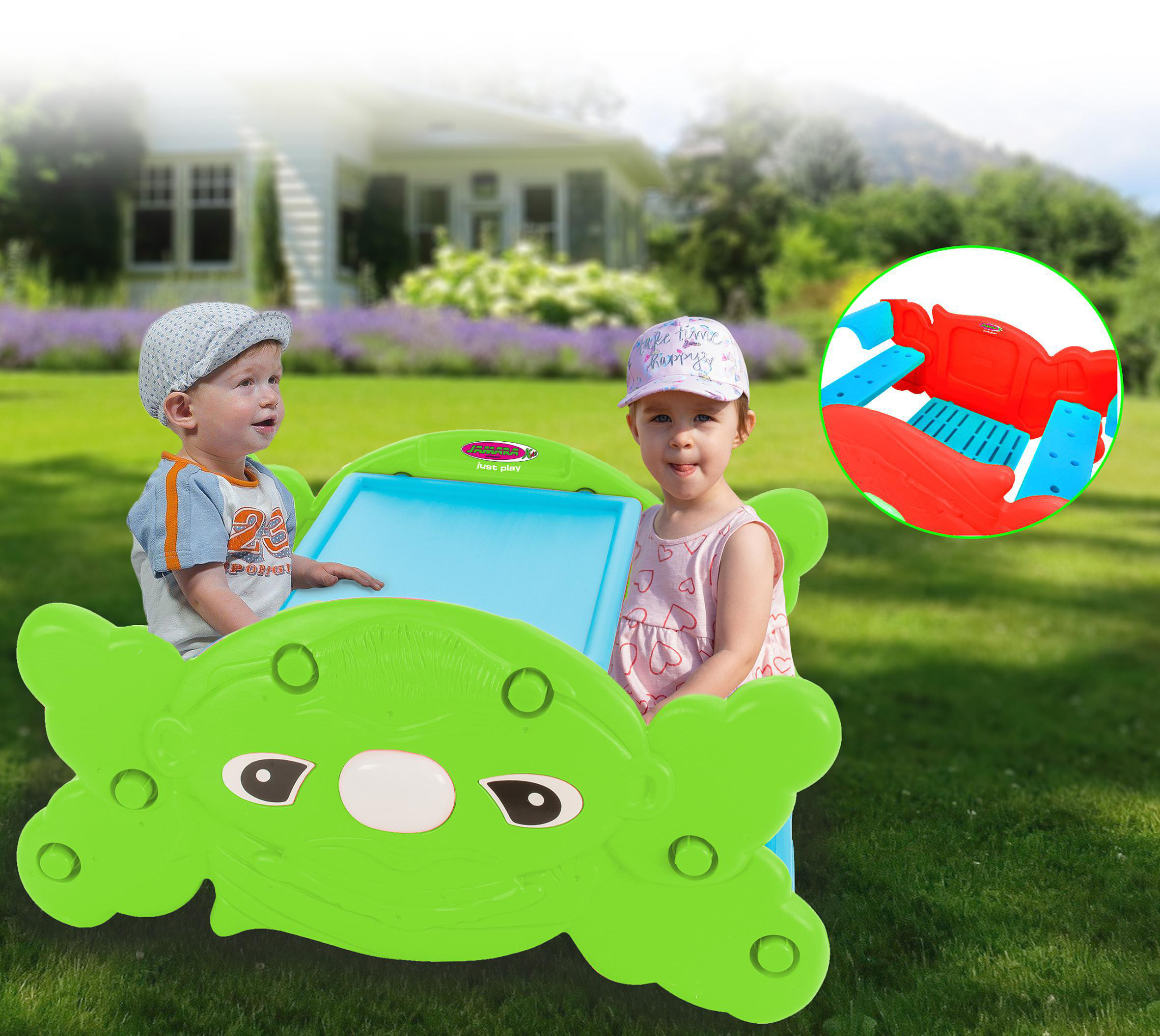 Zwei Kinder spielen an einem grünen, krabbenförmigen Spielzeug mit blauer Zeichenfläche.
