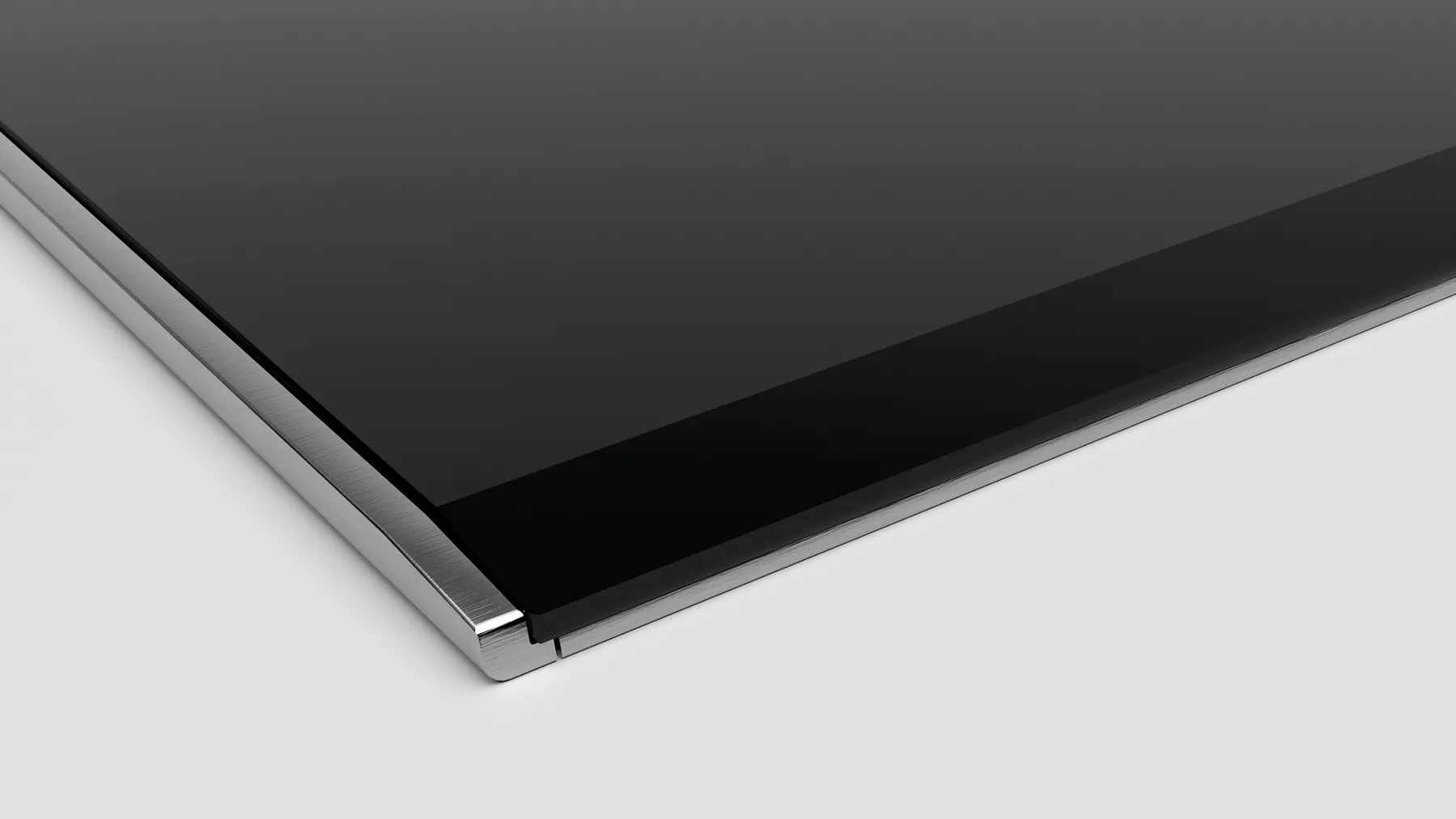 Gros plan sur une plaque de cuisson en verre noir avec un bord argenté, sur fond blanc.