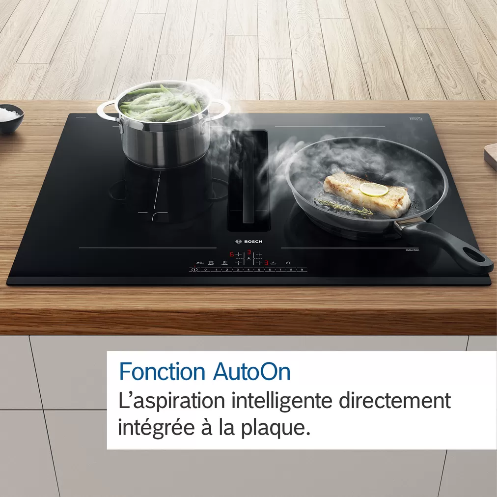 Table de cuisson à induction noire avec aliments cuisant dans une casserole et une poêle. Texte blanc superposé.